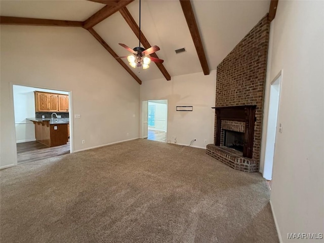 unfurnished living room with beamed ceiling, high vaulted ceiling, and a brick fireplace