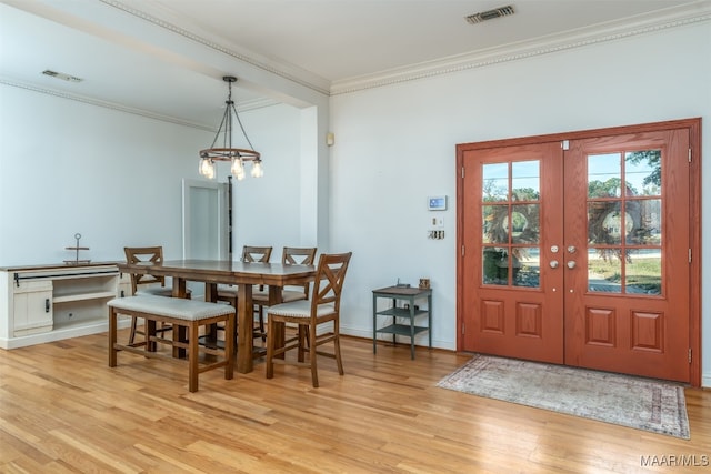 dining room featuring a notable chandelier, light hardwood / wood-style flooring, french doors, and ornamental molding