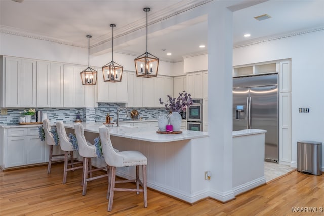 kitchen with stainless steel appliances, white cabinetry, and light wood-type flooring