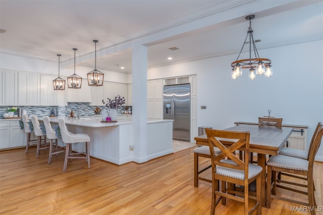 kitchen with stainless steel built in refrigerator, white cabinetry, and pendant lighting