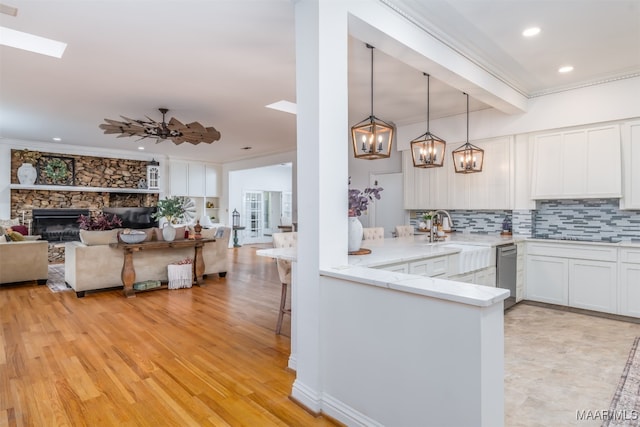 kitchen with white cabinetry, kitchen peninsula, crown molding, and light wood-type flooring