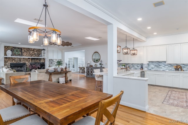 dining space with ornamental molding, a fireplace, light hardwood / wood-style floors, and sink