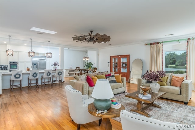 living room with ornamental molding, light wood-type flooring, and ceiling fan