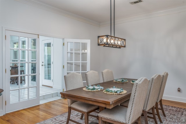 dining space with ornamental molding and light hardwood / wood-style flooring