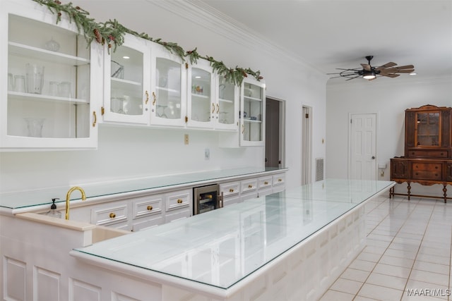 kitchen with ceiling fan, light tile patterned floors, ornamental molding, and white cabinets