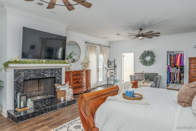 bedroom featuring wood-type flooring, ornamental molding, and a fireplace