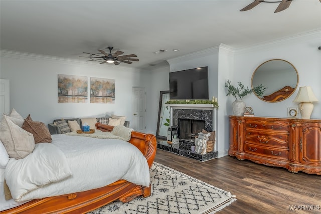 bedroom with ornamental molding, a premium fireplace, dark wood-type flooring, and ceiling fan