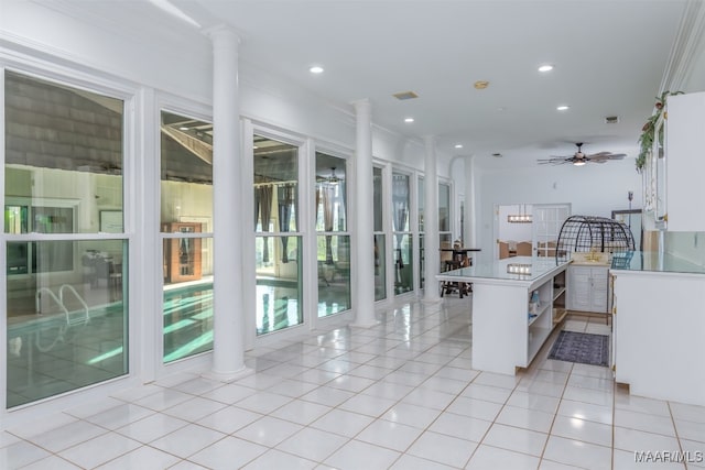 kitchen featuring light tile patterned floors, decorative columns, ornamental molding, ceiling fan, and white cabinetry