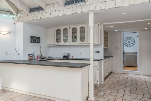 kitchen featuring white cabinetry, kitchen peninsula, and beam ceiling