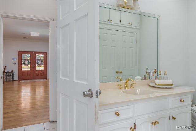 bathroom with ornamental molding, hardwood / wood-style floors, vanity, toilet, and french doors