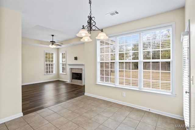 unfurnished living room featuring ceiling fan with notable chandelier and light hardwood / wood-style flooring