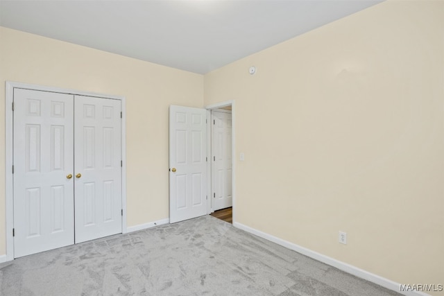 unfurnished bedroom with light colored carpet and a closet