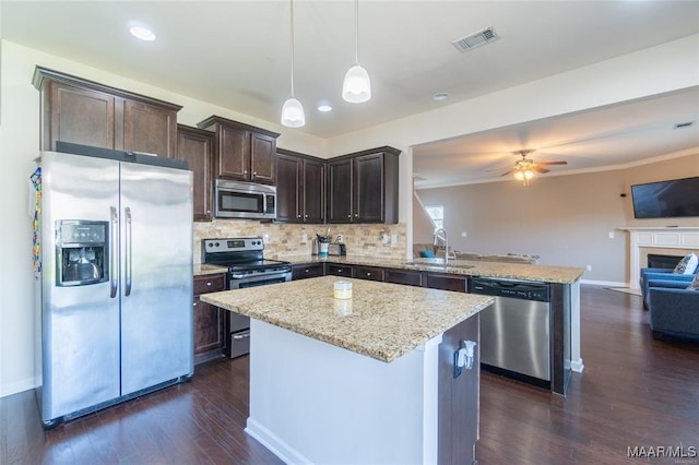 kitchen with stainless steel appliances, kitchen peninsula, sink, dark hardwood / wood-style floors, and pendant lighting