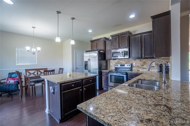 kitchen featuring stainless steel appliances, sink, a kitchen island, dark wood-type flooring, and pendant lighting