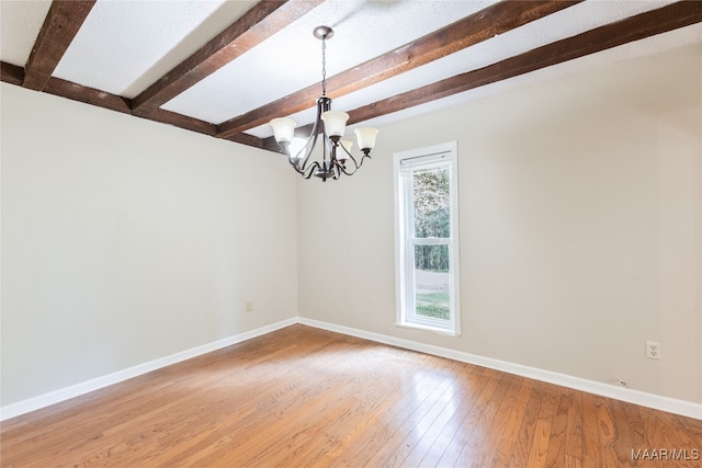 unfurnished room featuring plenty of natural light, a notable chandelier, hardwood / wood-style flooring, and beam ceiling