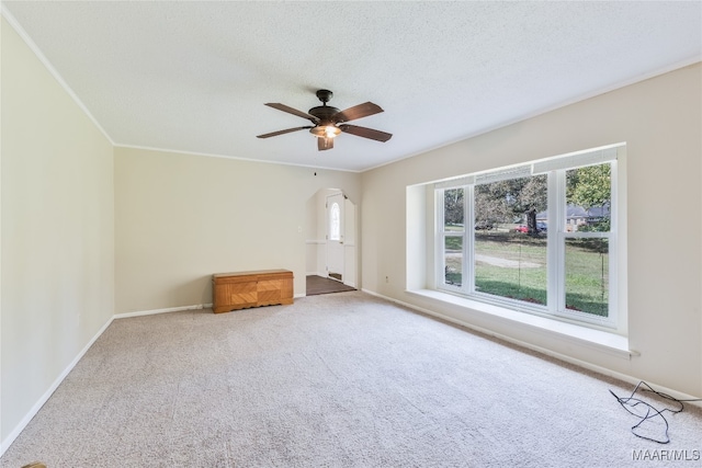 unfurnished living room featuring ceiling fan, a textured ceiling, crown molding, and carpet