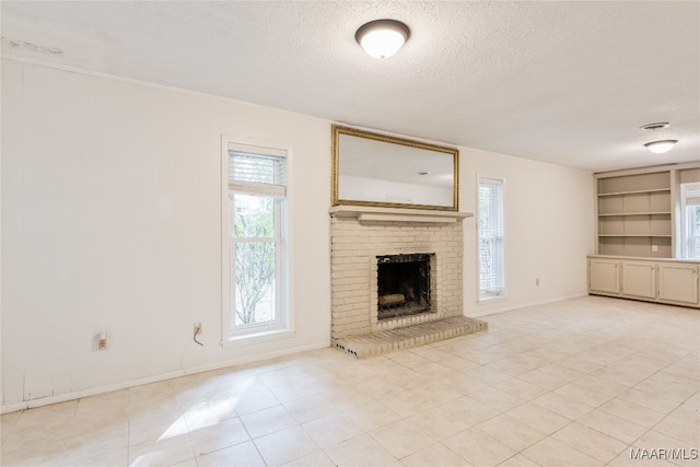 unfurnished living room with a fireplace, a textured ceiling, light tile patterned floors, and built in shelves