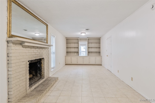 unfurnished living room featuring a fireplace, a textured ceiling, and light tile patterned floors