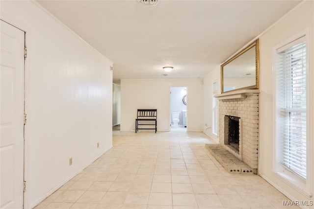 unfurnished living room with a brick fireplace, a wealth of natural light, light tile patterned floors, and crown molding