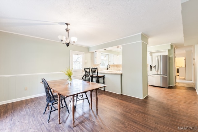 dining space featuring a textured ceiling, dark hardwood / wood-style flooring, and crown molding