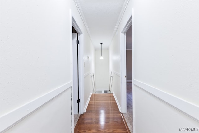 hall with dark hardwood / wood-style floors, a textured ceiling, and crown molding