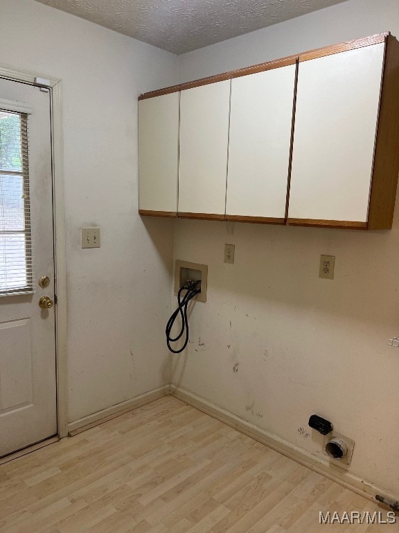 laundry room featuring light wood-type flooring, cabinets, a textured ceiling, and hookup for a washing machine