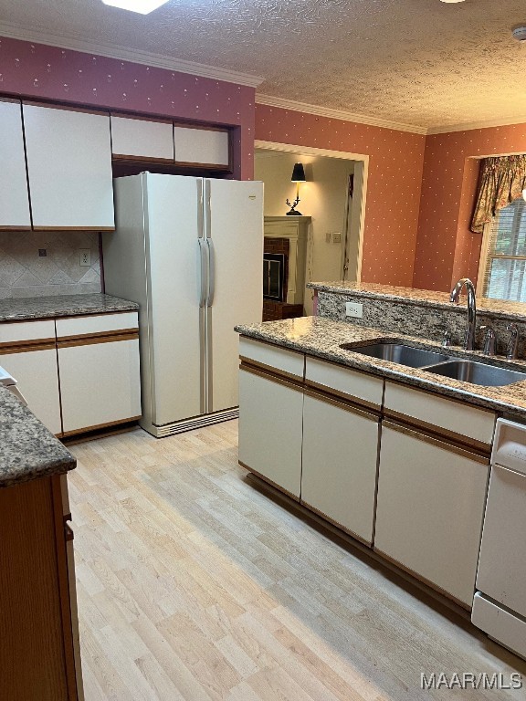 kitchen featuring white appliances, white cabinetry, sink, and light hardwood / wood-style floors