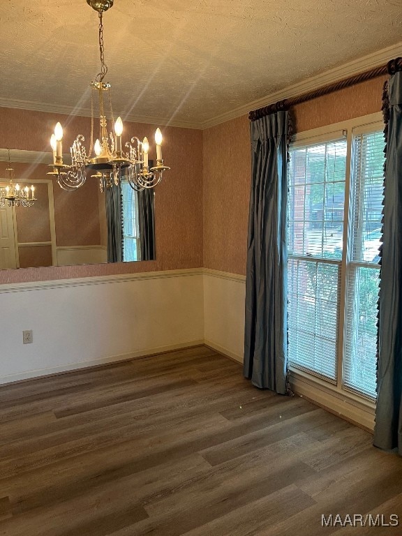 unfurnished dining area featuring hardwood / wood-style floors, a notable chandelier, ornamental molding, and a textured ceiling