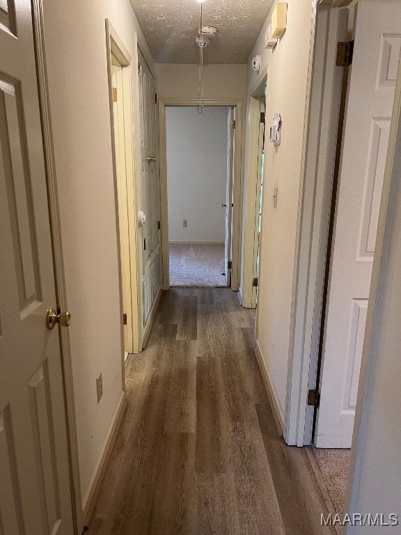 hall featuring a textured ceiling and dark hardwood / wood-style floors