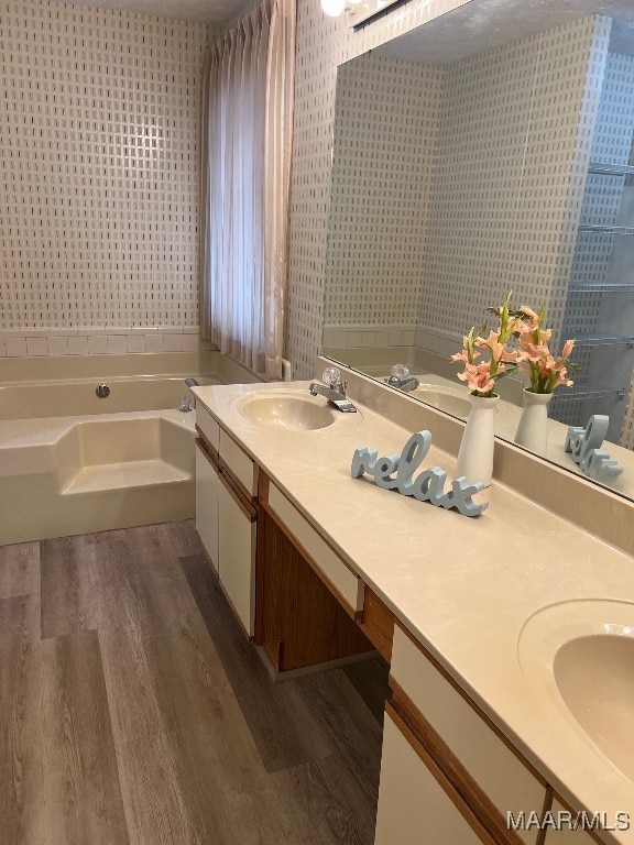 bathroom featuring hardwood / wood-style floors, vanity, and a washtub