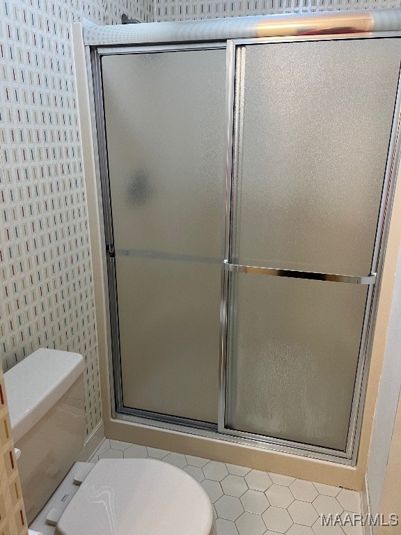 bathroom featuring toilet and a shower with door