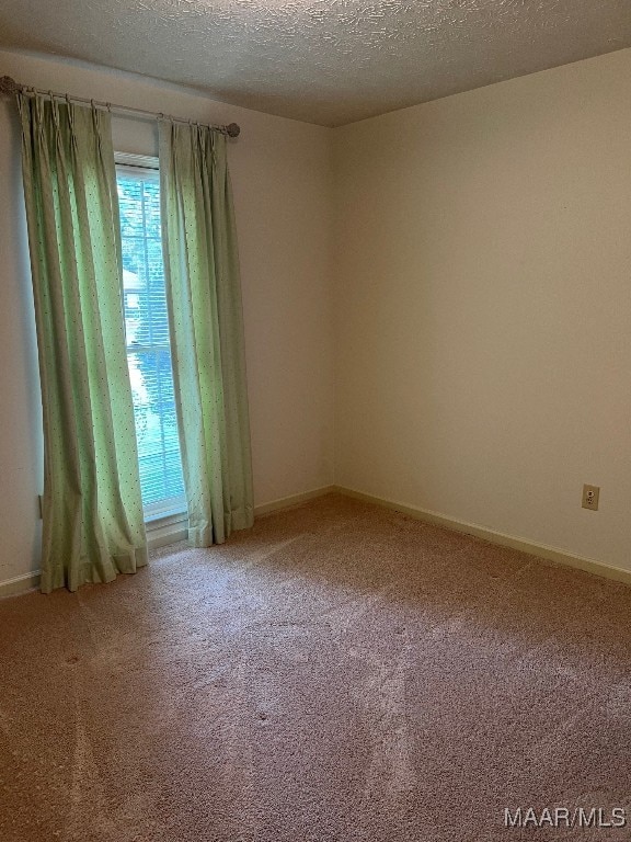 carpeted empty room featuring a textured ceiling