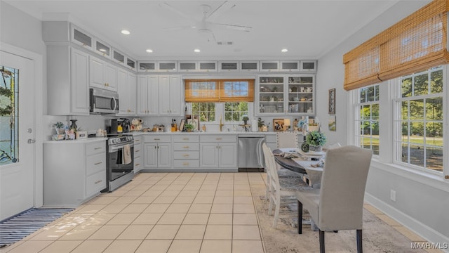 kitchen featuring plenty of natural light, appliances with stainless steel finishes, light tile patterned floors, and white cabinets