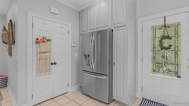 kitchen with a wealth of natural light, light tile patterned floors, crown molding, and stainless steel fridge