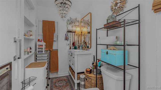 bathroom featuring heating unit, sink, toilet, and a notable chandelier