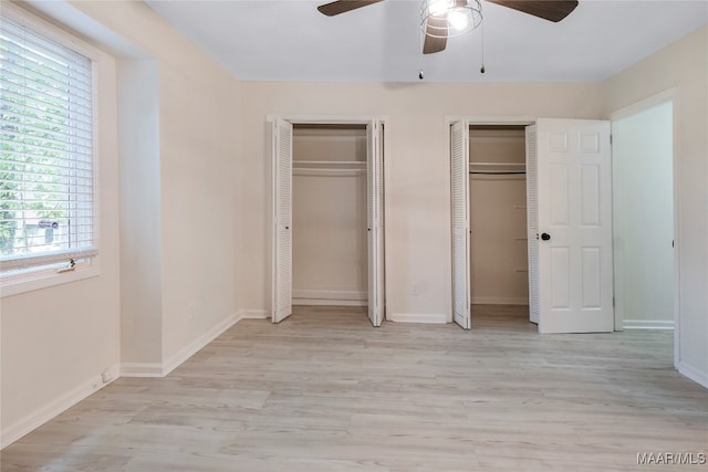 unfurnished bedroom with two closets, ceiling fan, and light hardwood / wood-style flooring