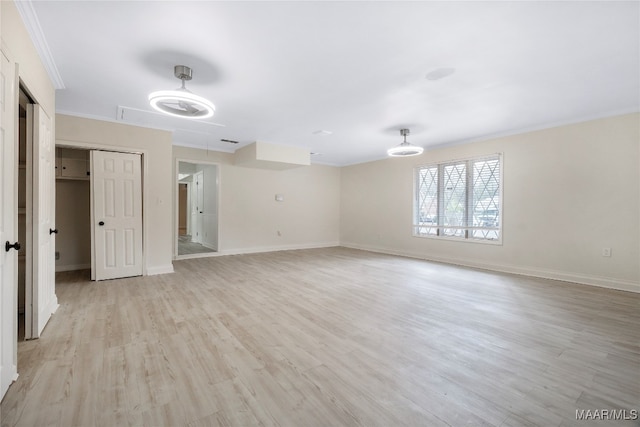 empty room featuring light wood-type flooring and ornamental molding