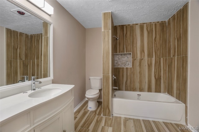 full bathroom featuring washtub / shower combination, a textured ceiling, toilet, and vanity