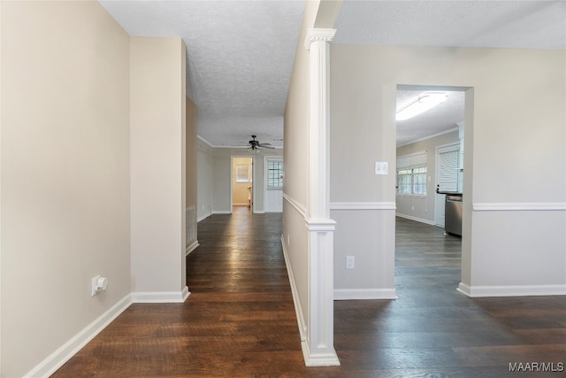 corridor with a wealth of natural light, a textured ceiling, and dark hardwood / wood-style flooring