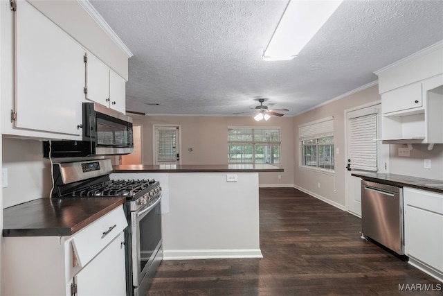 kitchen featuring crown molding, appliances with stainless steel finishes, white cabinets, dark wood-type flooring, and kitchen peninsula