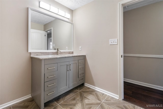 bathroom with vanity, parquet flooring, and a textured ceiling