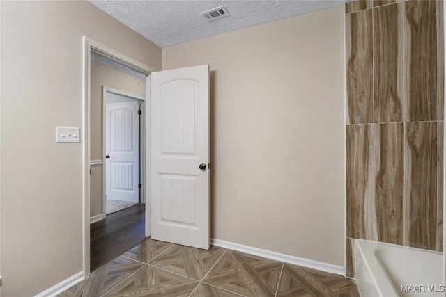 interior space with a textured ceiling and parquet flooring