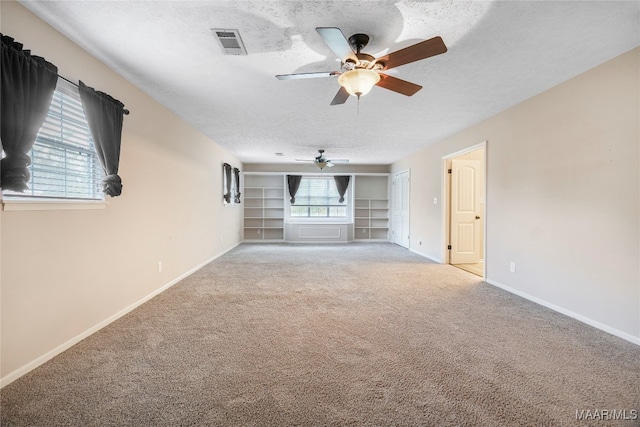 unfurnished living room featuring a textured ceiling, light carpet, ceiling fan, and plenty of natural light