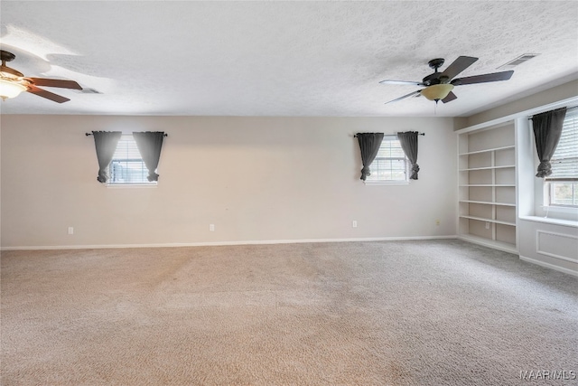 carpeted spare room featuring a textured ceiling, plenty of natural light, and ceiling fan