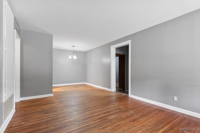 unfurnished room with dark wood-type flooring and a chandelier