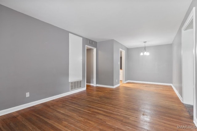 spare room with hardwood / wood-style floors and an inviting chandelier