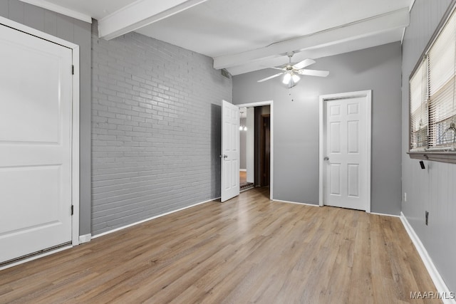 unfurnished bedroom featuring ceiling fan, beamed ceiling, brick wall, and light wood-type flooring