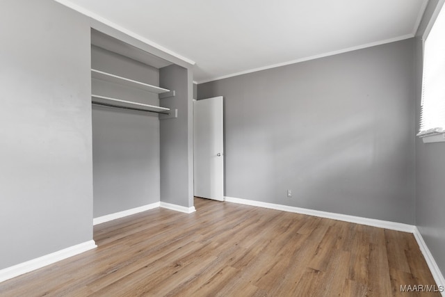 unfurnished bedroom with crown molding, a closet, and light hardwood / wood-style floors