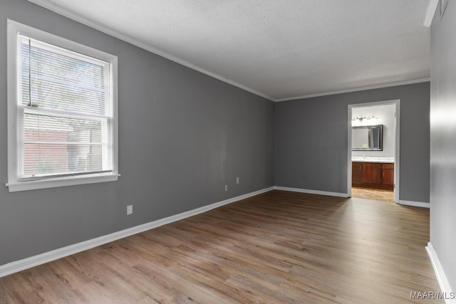 interior space with crown molding, a textured ceiling, and light wood-type flooring