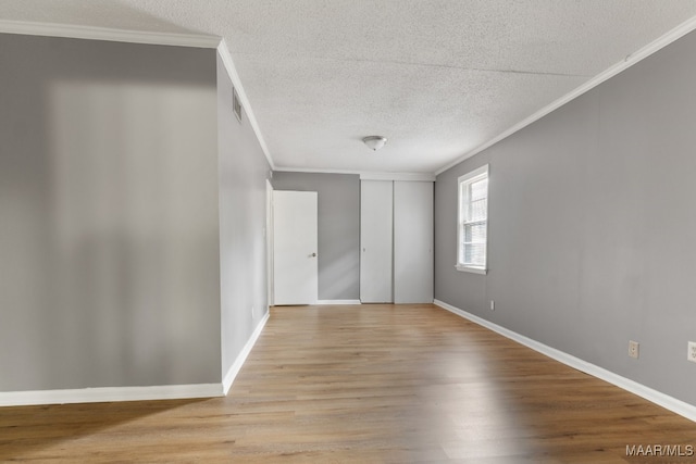 unfurnished bedroom featuring light wood-type flooring, ornamental molding, and a textured ceiling